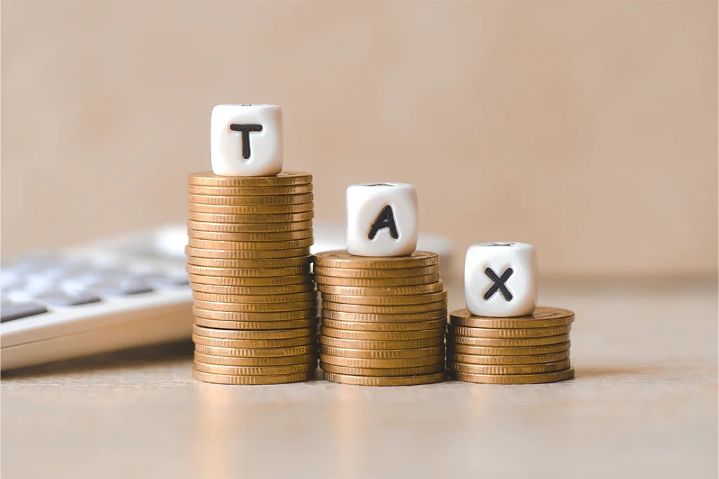 Kolikot ja TAX-kuutiot kuvaamassa arvonlisäverotusta – talouden hallinta ja verotus yrityksessä.